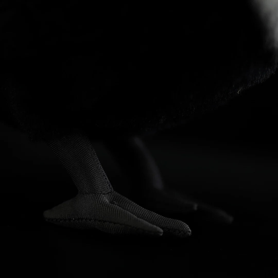 Close-up of the feet on a Collared Crow plush toy, featuring detailed texture and lifelike design