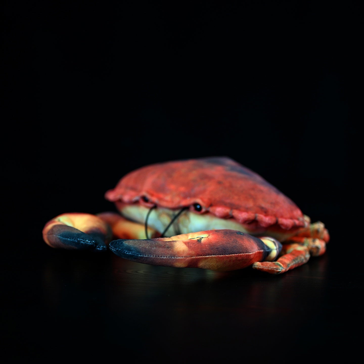 Side view of a soft stuffed crab plush toy, showcasing vibrant colors and realistic claws