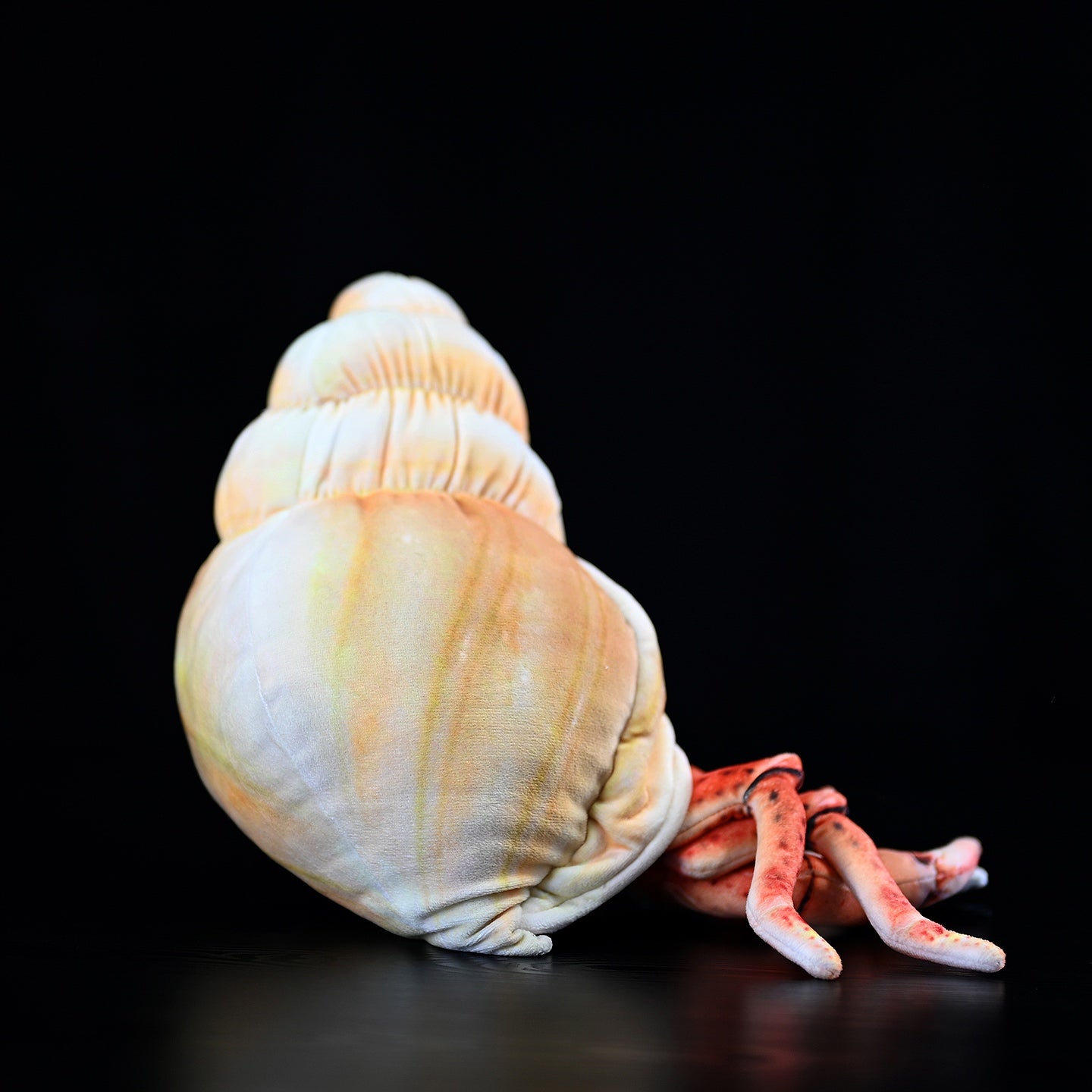 Side view of hermit crab plush with intricate legs and a vibrant, detailed shell