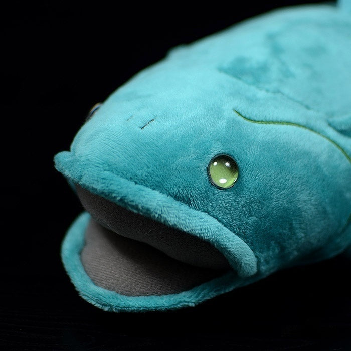 Close-up of coelacanth plush toy's face, showcasing lifelike green eyes and soft material design