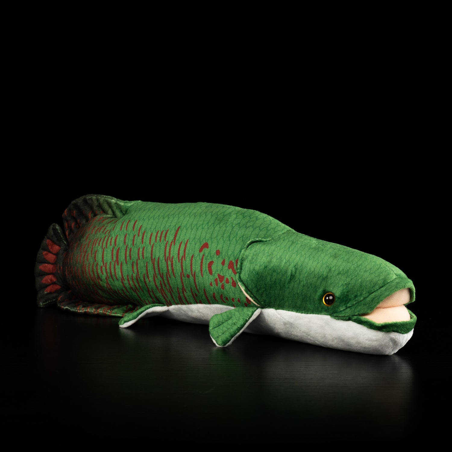 Side angle of an Arapaima gigas fish plush with vivid green scales and red patterns by SoftDaysLab
