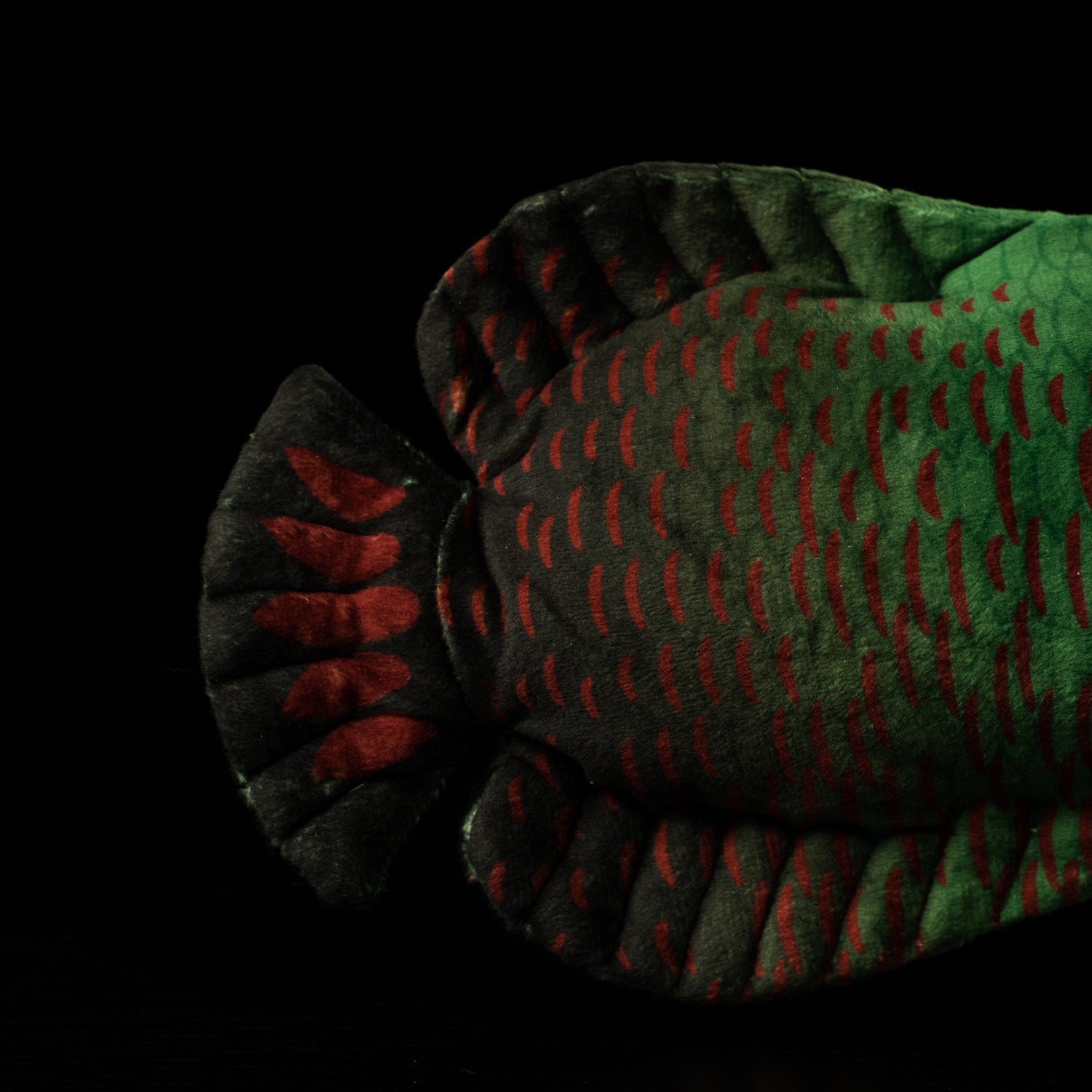 Tail close-up of the Arapaima gigas plush toy by SoftDaysLab, showcasing intricate red and green freshwater fish patterns