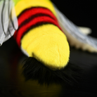 Close-up of the tail end of a coffee bee hawkmoth plush toy, emphasizing its fluffy black tail and vibrant body stripes