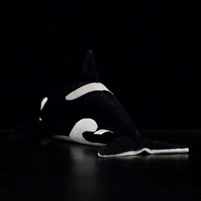 Rear view of soft orca whale plush toy, showing its detailed tail and smooth black-and-white finish