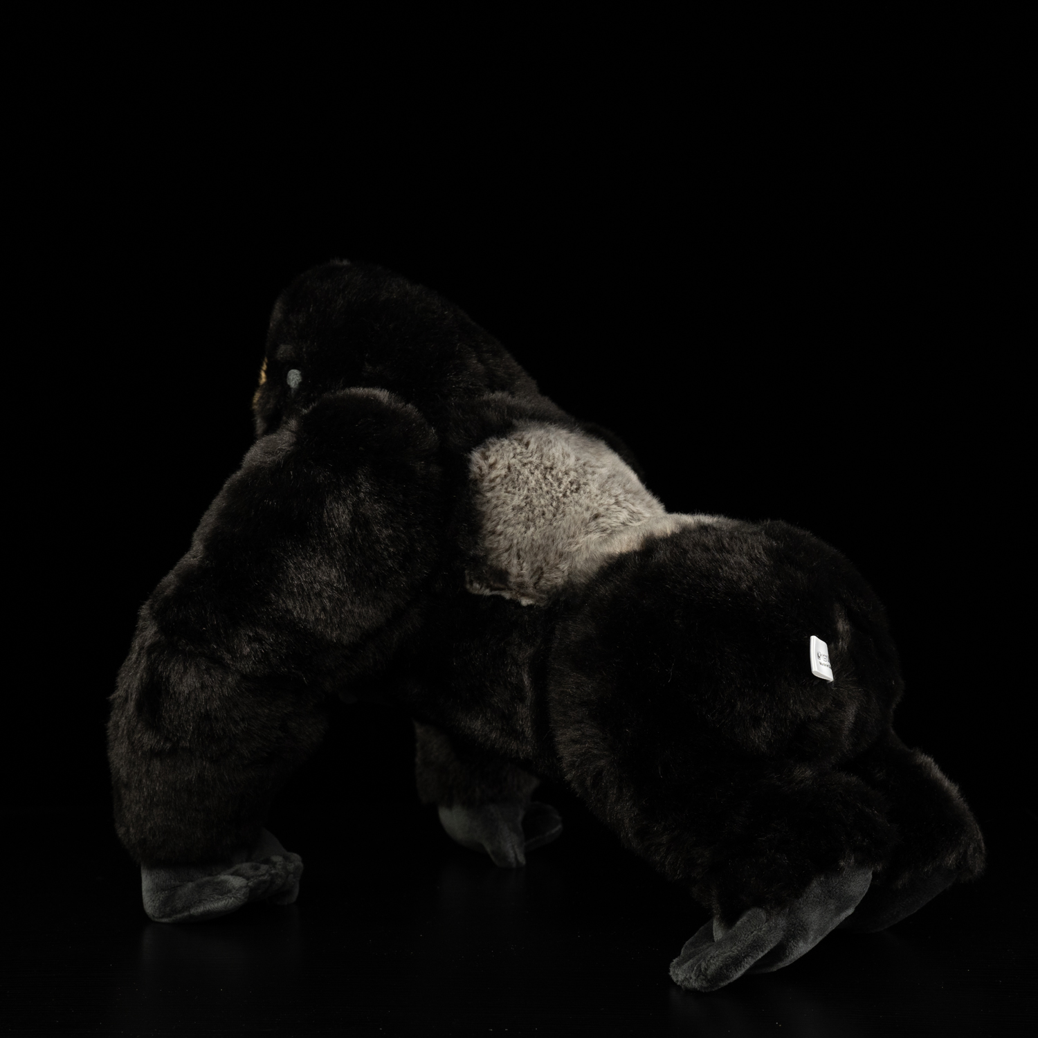 Rear view of a silverback gorilla plush toy emphasizing its realistic fur and strong posture
