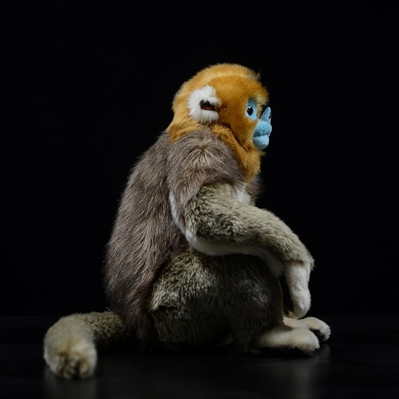 Side view of a golden snub-nosed monkey plush toy sitting, showcasing its lifelike fur and unique design