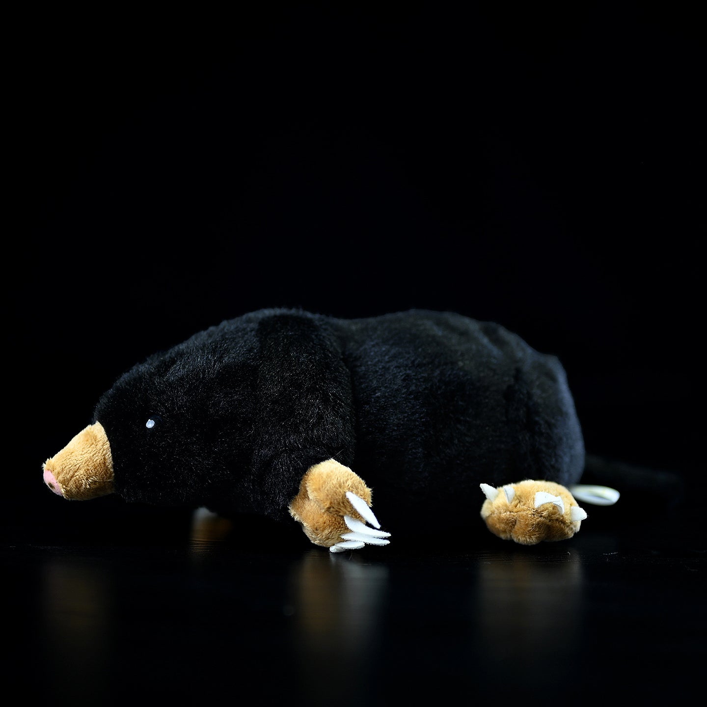 Side view of a realistic lying mole plush toy with soft black fur and detailed claws, perfect for animal lovers
