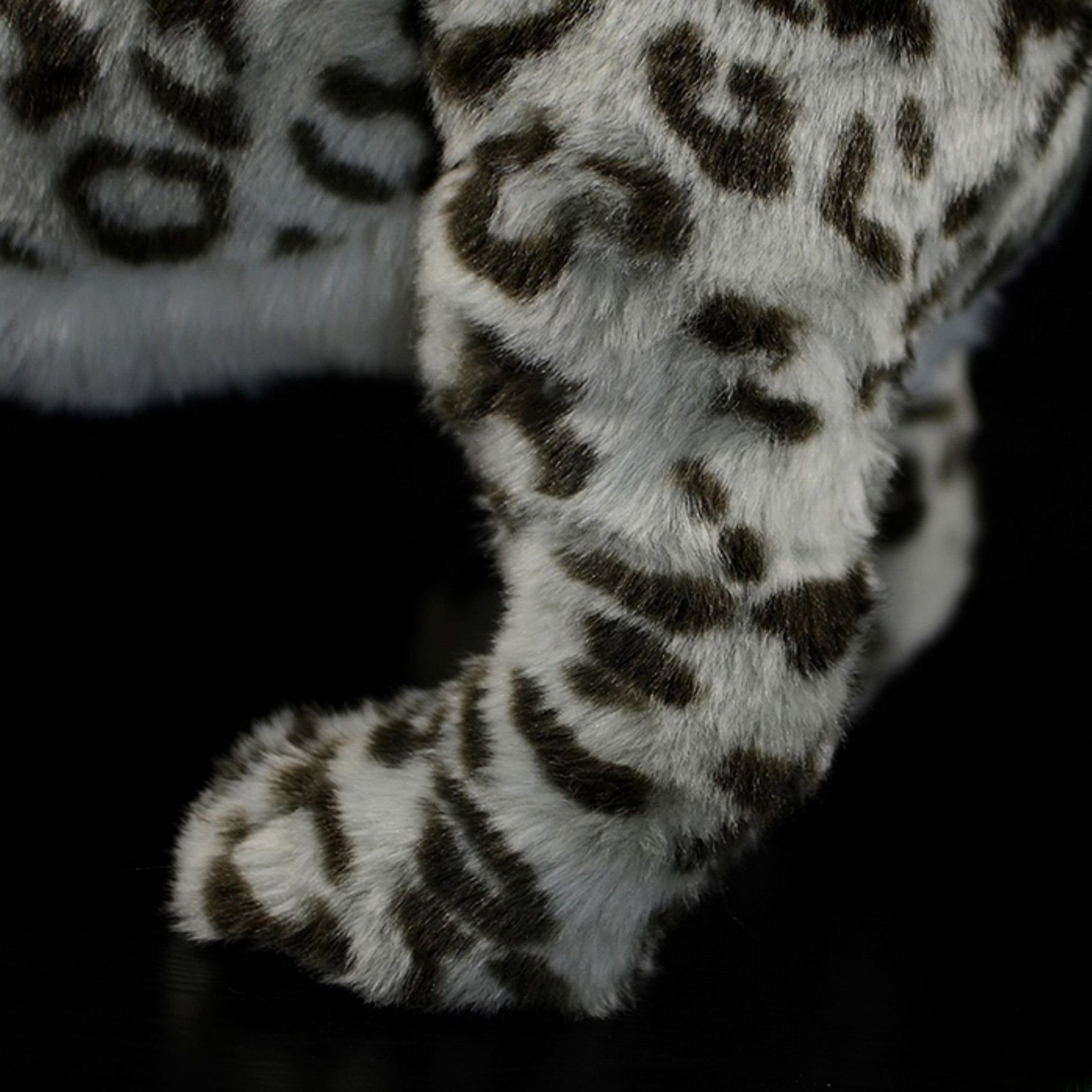 Close-up of snow leopard plush toy’s paw, showcasing soft and detailed fur design