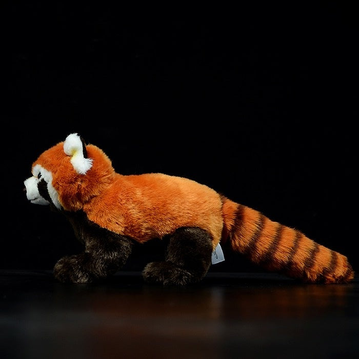 Profile view of a red panda plush toy, highlighting its realistic tail and soft, cuddly design