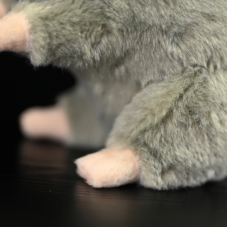 Close-up of a standing grey mouse plush toy’s paws, showing its soft and delicate design