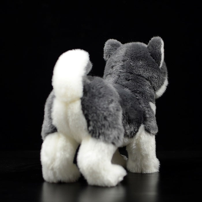 Rear view of an Alaskan Malamute plush toy, featuring a curled white tail and detailed fur texture