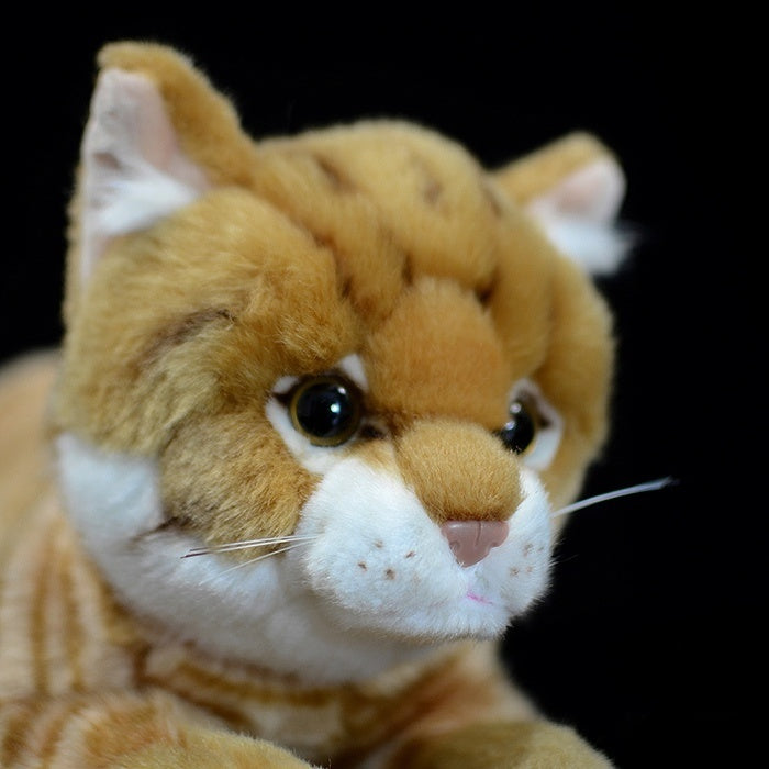Close-up of the lifelike face of the orange tabby plush toy, with realistic eyes and soft fur