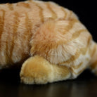 Close-up of the plush toy’s soft paw and striped body, resembling a real orange tabby cat