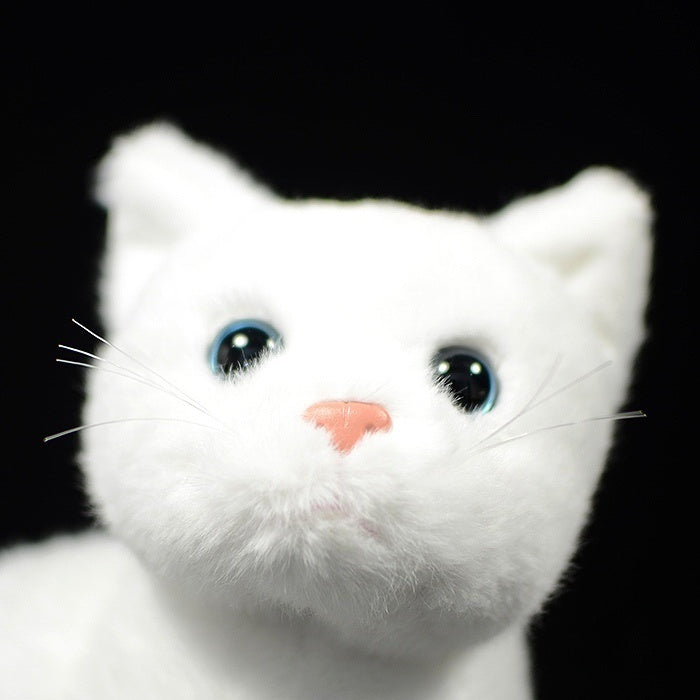 Close-up of the white cat plush toy's face, featuring lifelike blue eyes and a soft pink nose