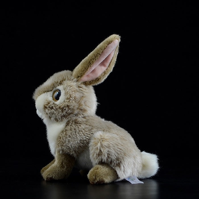 Side profile of realistic brown hare rabbit plush toy, highlighting its soft fur and natural pose