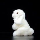 Side view of a white lop-eared rabbit plush, showcasing its lifelike floppy ears and soft texture