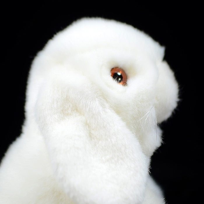 Close-up of the white lop-eared rabbit plush's face, with detailed eyes and lifelike fur texture