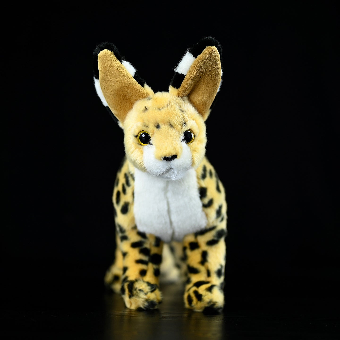 Front view of a standing serval cat plush toy featuring large ears, realistic spots, and soft fur