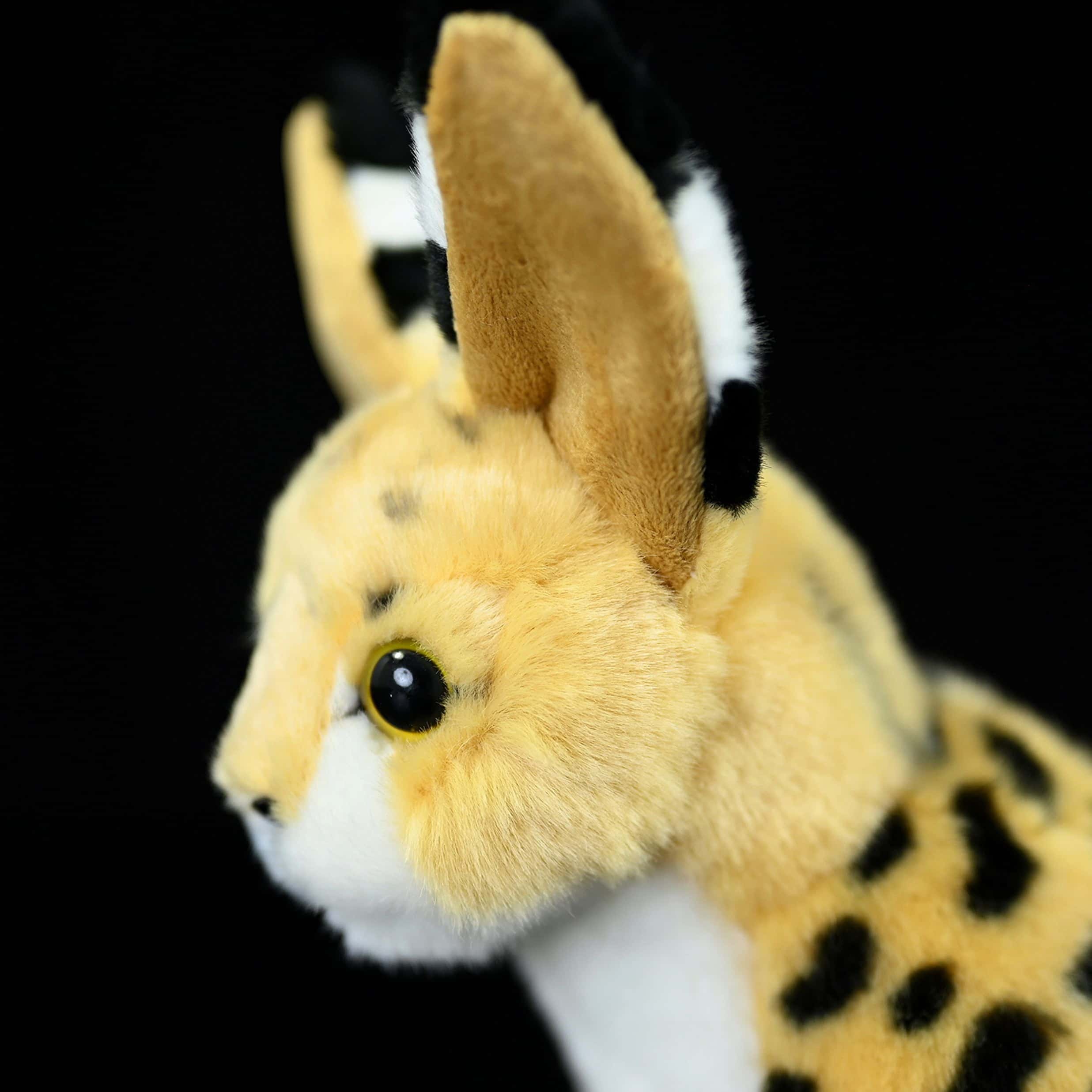 Close-up side profile of a standing serval cat plush toy showing its realistic ears and soft fur