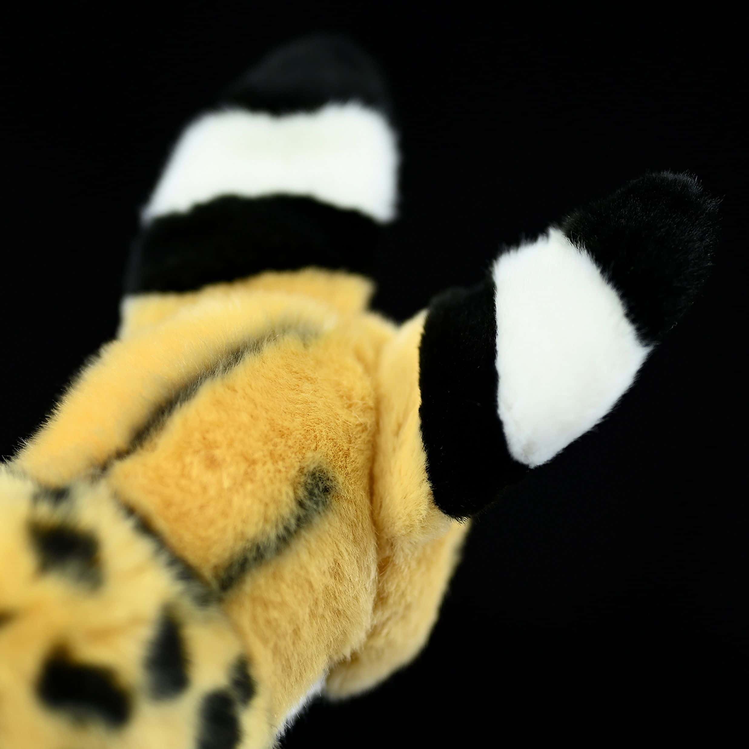 Close-up of the black-tipped ears of a standing serval cat plush toy, designed for lifelike detail