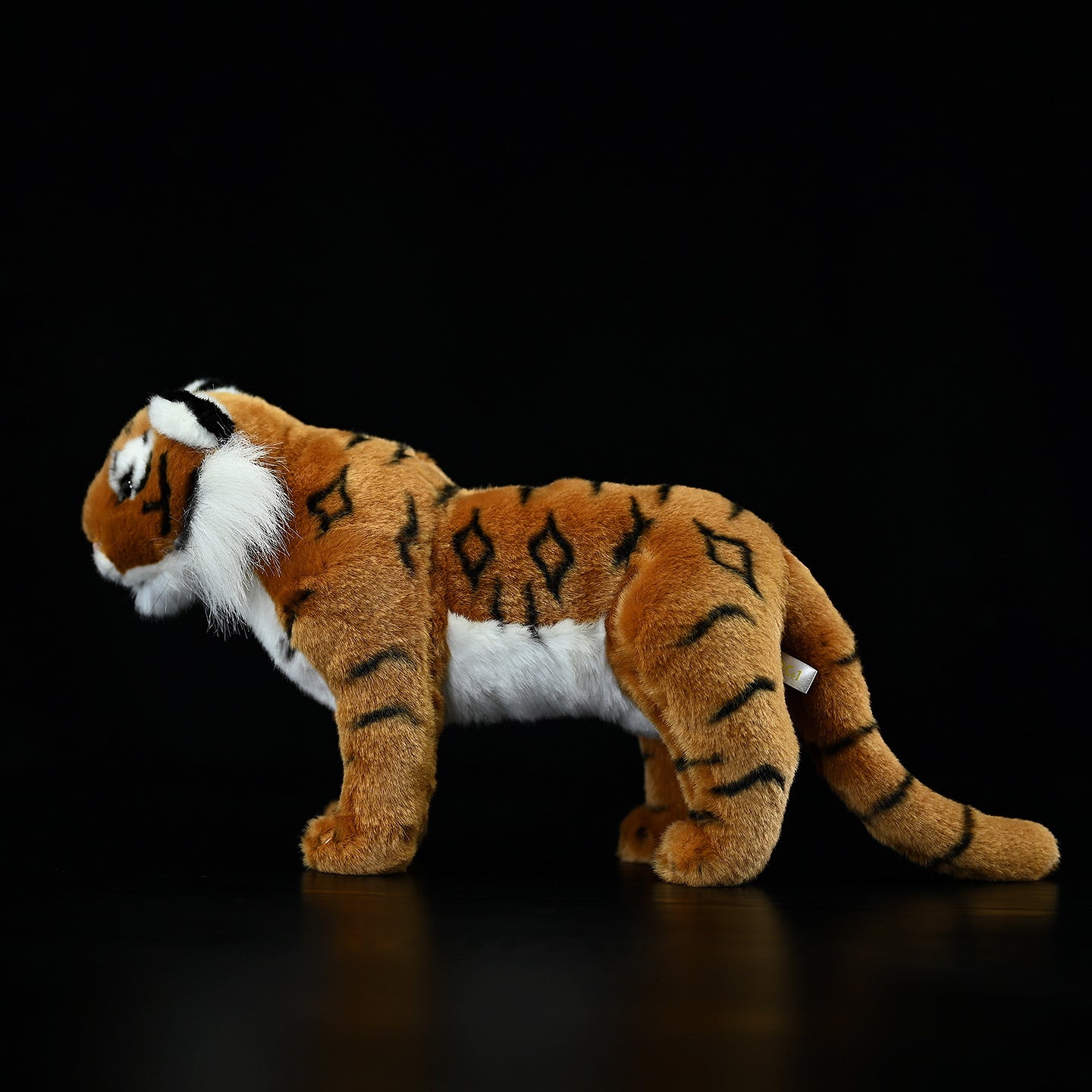 Side profile of a soft tiger plush toy, highlighting its striking stripes and natural pose