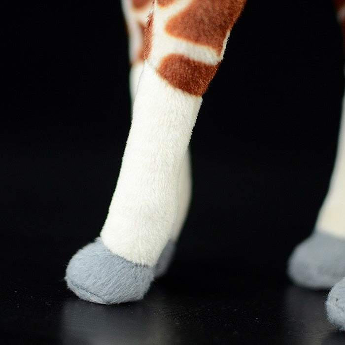 Close-up of the giraffe plush toy's legs, featuring soft fabric and detailed coloring