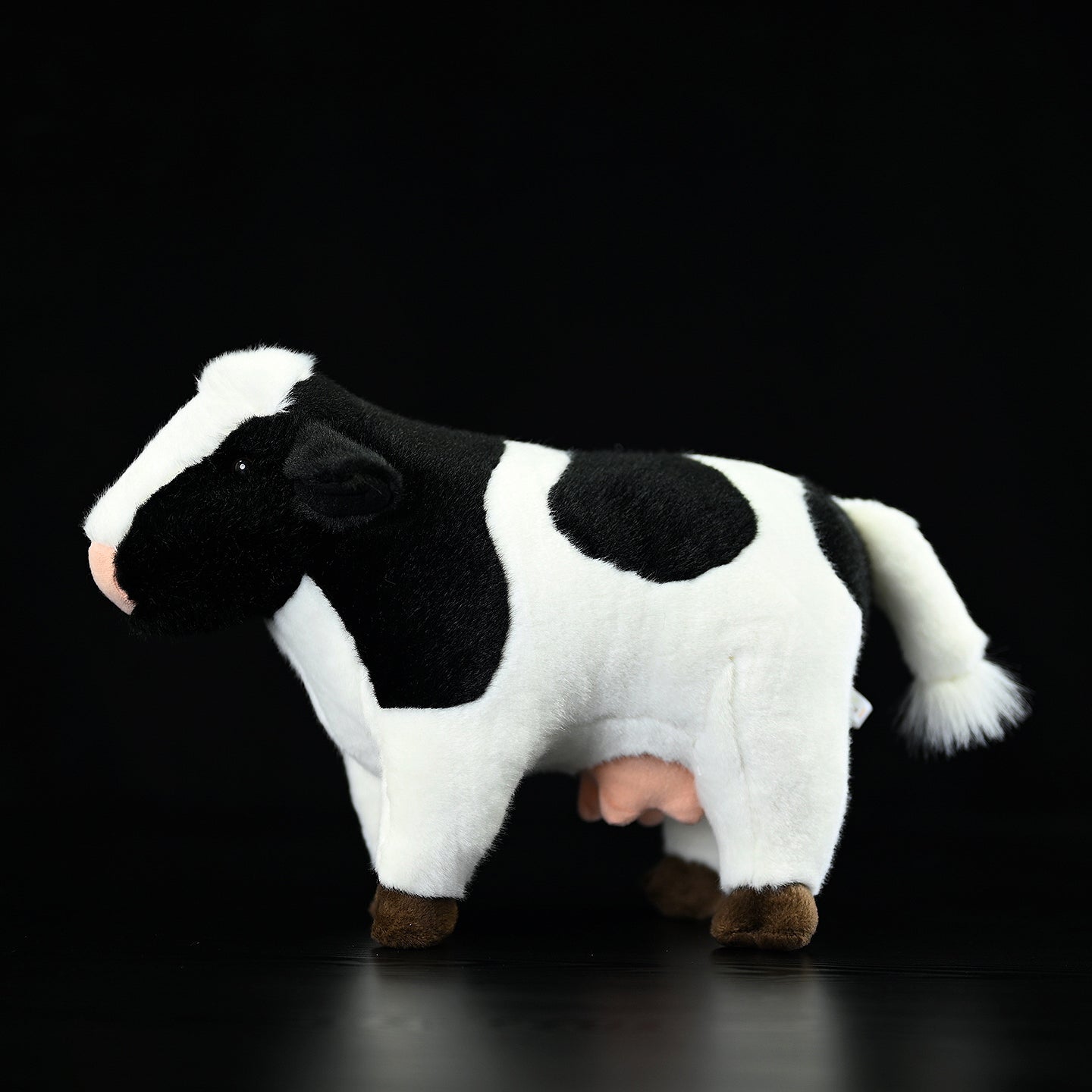 Side profile of a lifelike Holstein cow plush toy with realistic markings and adorable details