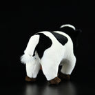 Back view of a plush Holstein cow toy, showcasing its tail and realistic black-and-white design