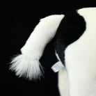 Close-up of the tail on a plush black-and-white Holstein cow, highlighting its lifelike design