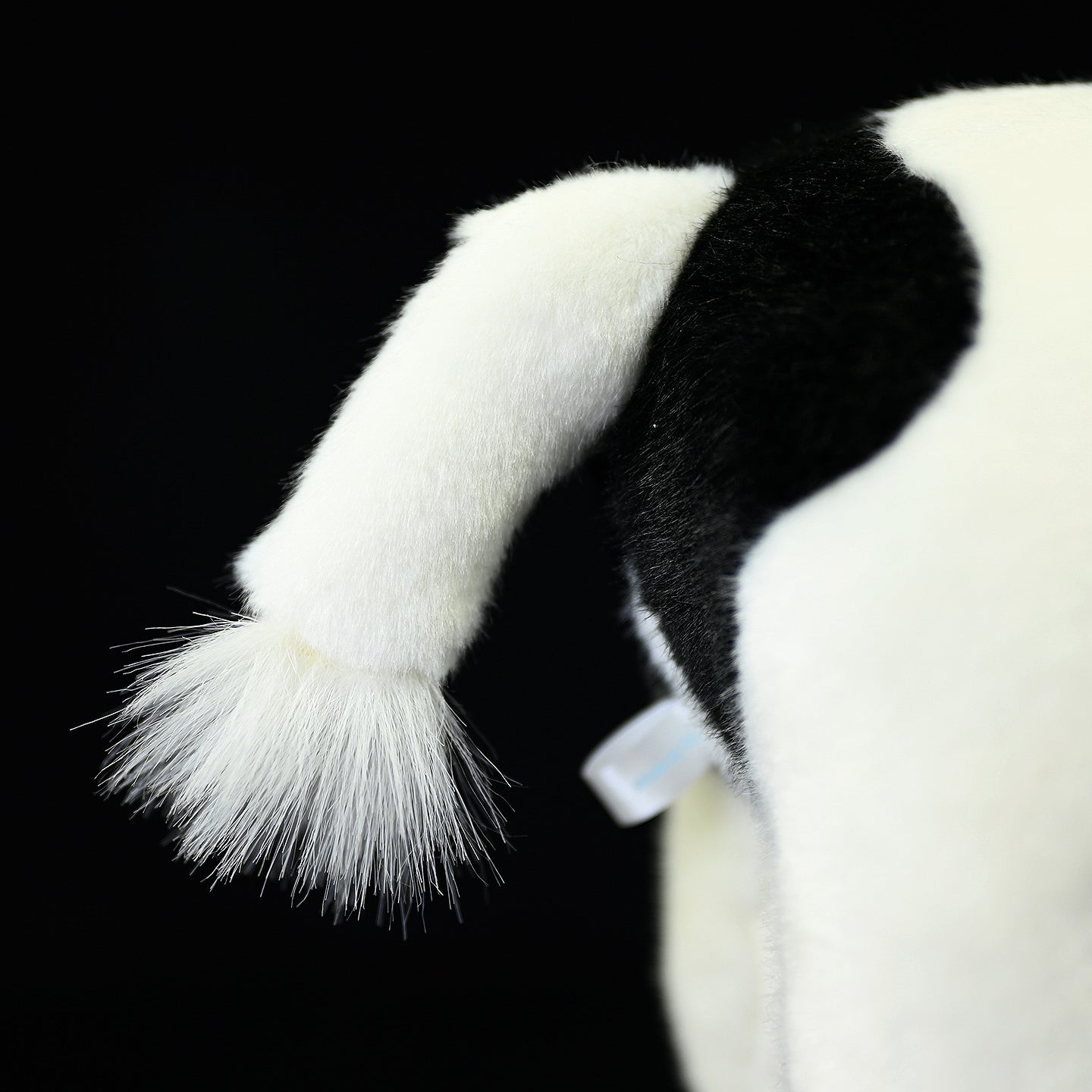 Close-up of the tail on a plush black-and-white Holstein cow, highlighting its lifelike design