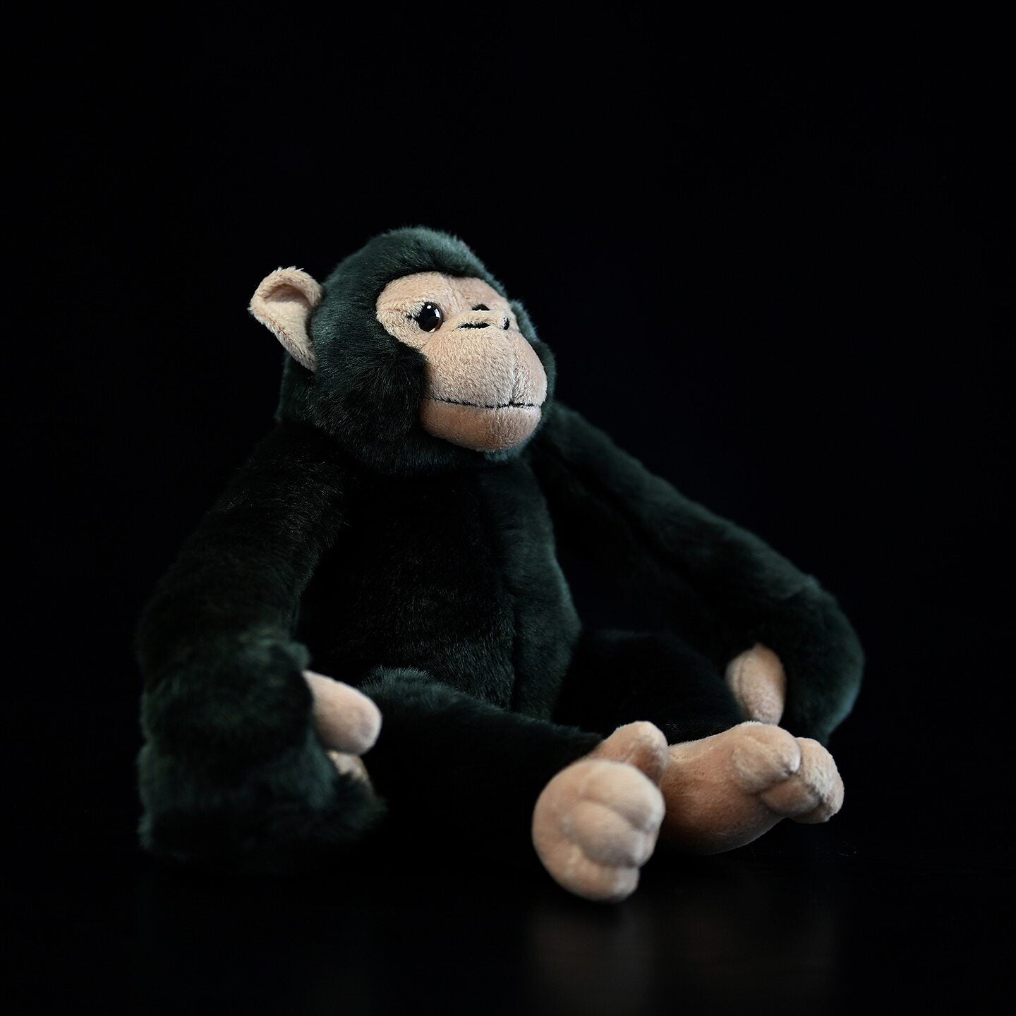Side view of a sitting chimpanzee plush with soft fur and realistic features, a charming stuffed animal toy
