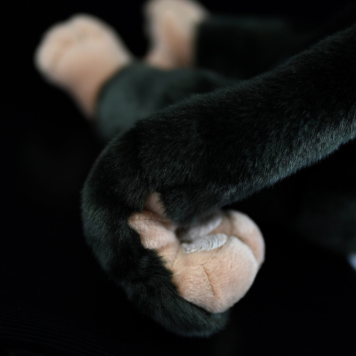 Detail shot of plush chimpanzee's hand, crafted for realism with soft textures and intricate stitching
