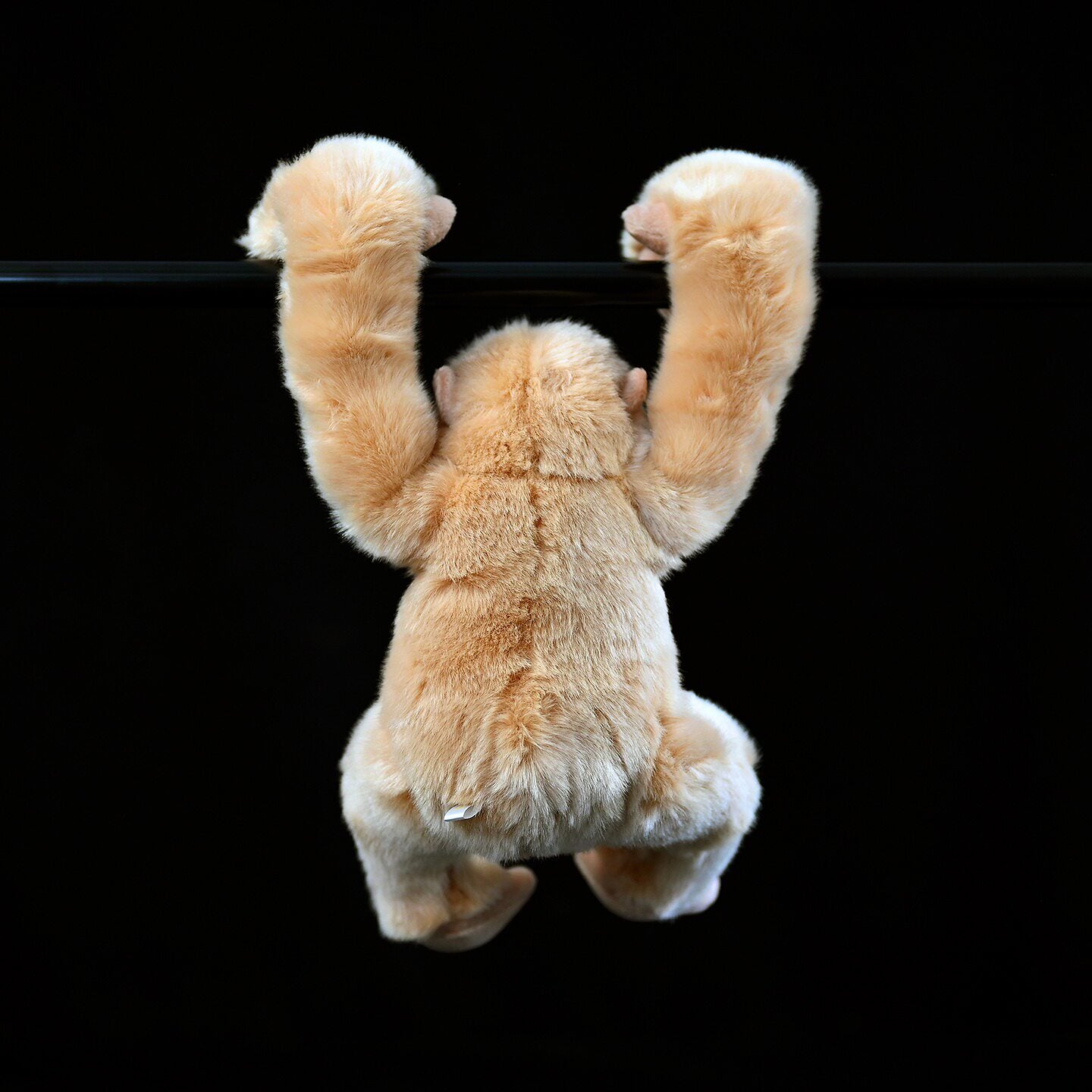 Back view of lifelike gibbon plush hanging from a bar, lifelike SoftDaysLab gibbon stuffed animal