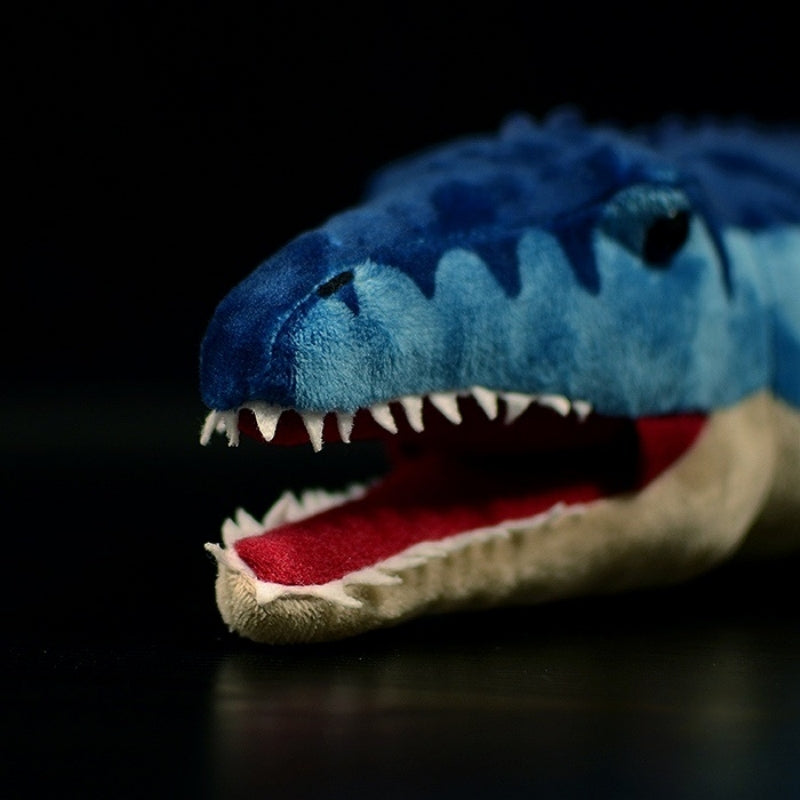 Close-up of Mosasaurus toy head featuring textured blue fabric, black eyes, and sharp white teeth