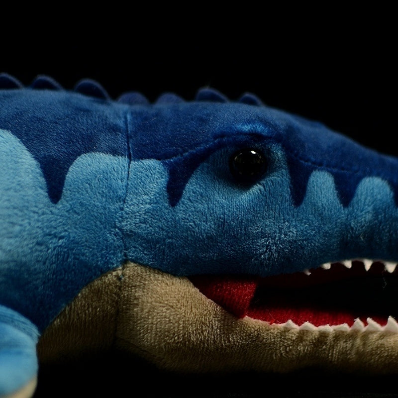 Close-up of Mosasaurus toy head featuring textured blue fabric, black eyes, and sharp white teeth