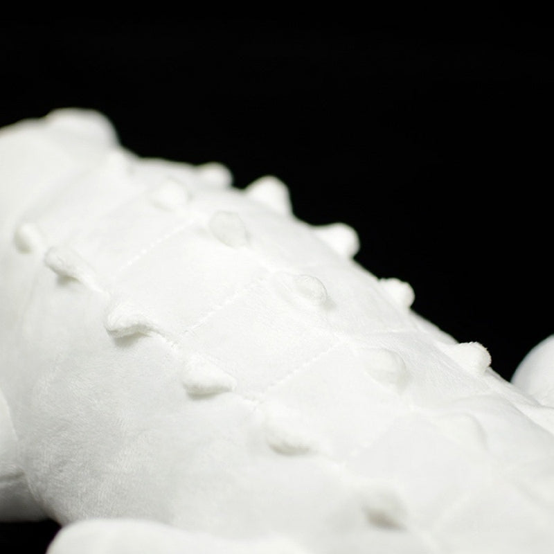 Close-up of white stuffed alligator's textured back featuring soft spikes and sewn details