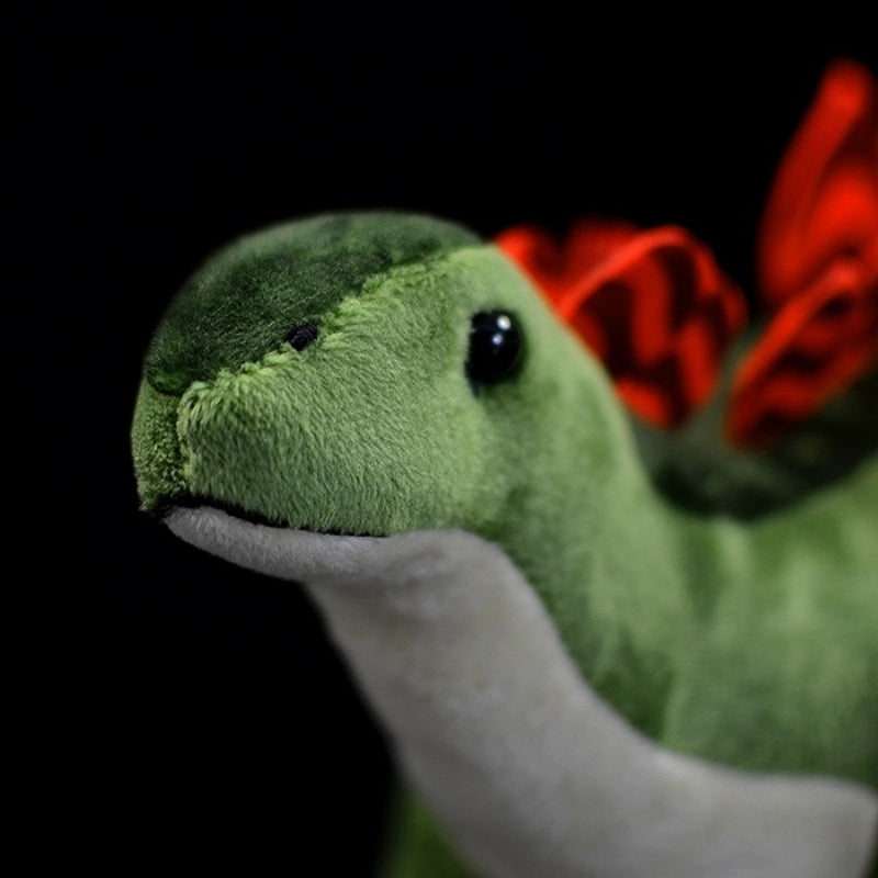 Close-up of Stegosaurus dinosaur plush head, showcasing soft green fabric and lifelike eyes