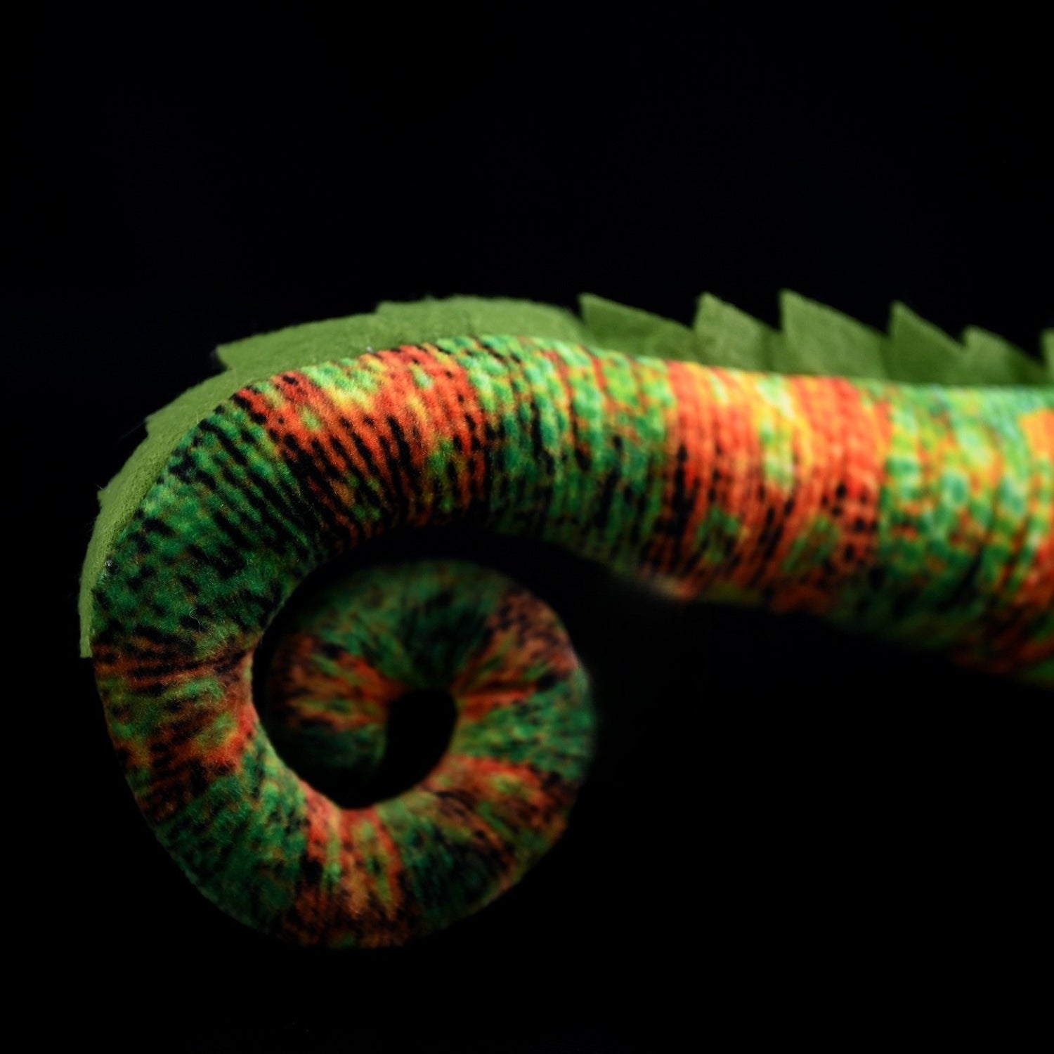 Detailed view of the curled tail on the veiled chameleon plush with realistic color patterns